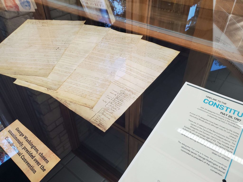 Close up shot of what is displayed in the case for Constitution day. A facsimile of the Constitution is visible as well as a corner of the timeline to the Constitution. 