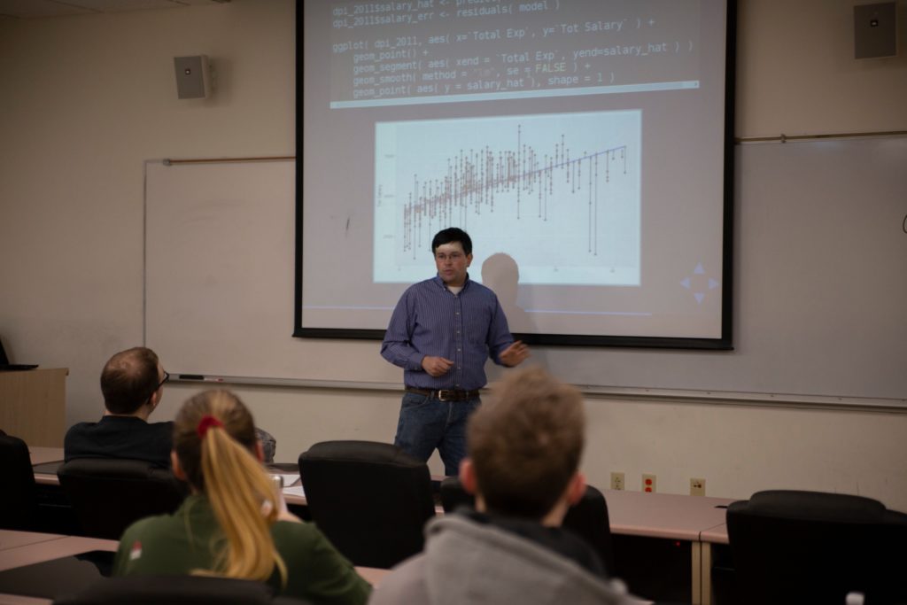 Professor Arnold Shober stands in front of a graph in a classroom.