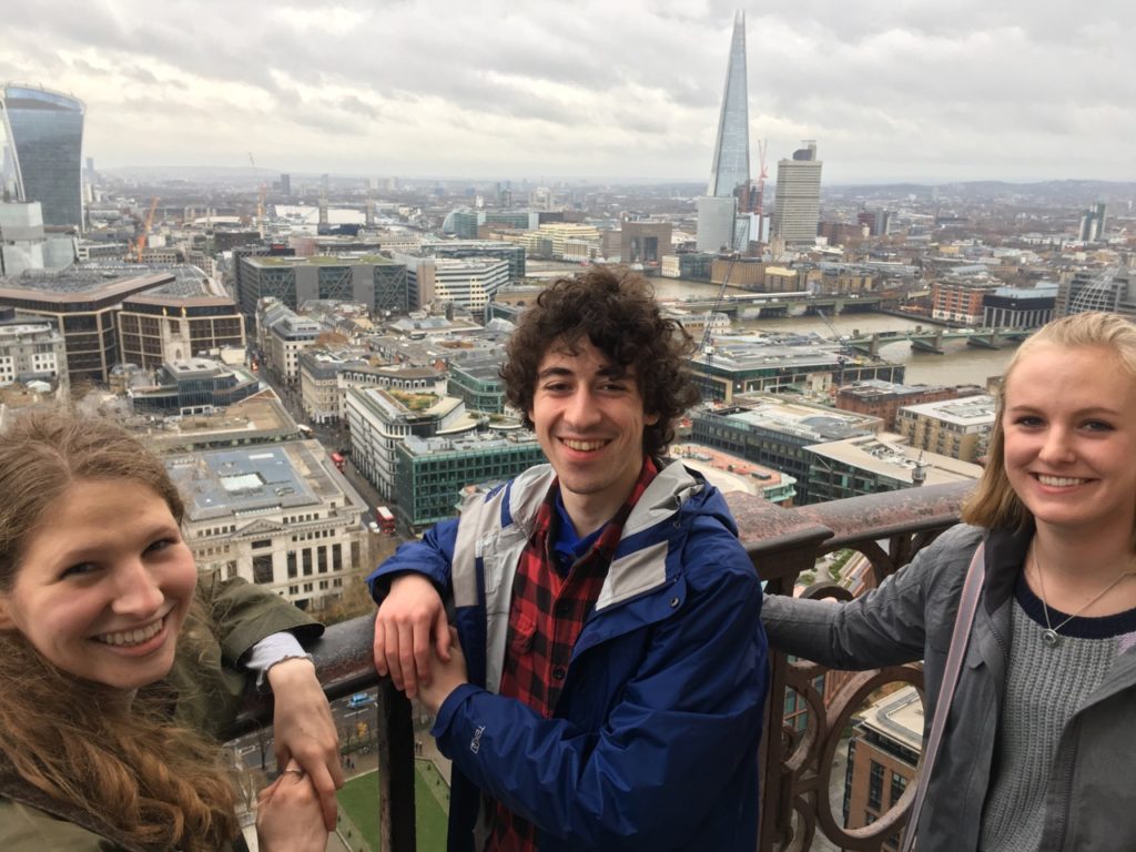 Three students pose on top of St. Paul's Cathedra with the London skyline in the background.