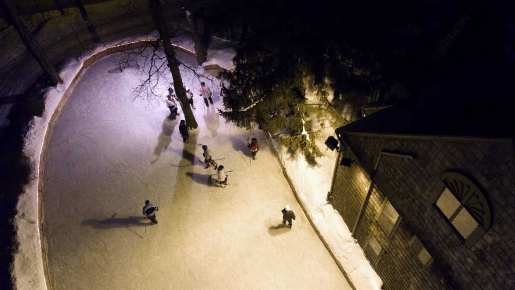 Aerial view of hockey players making their way across the ice on the McKee outdoor rink.