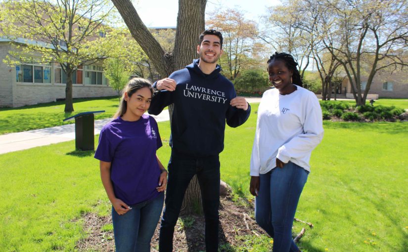 Three Lawrence students wearing Lawrence attire outdoors.