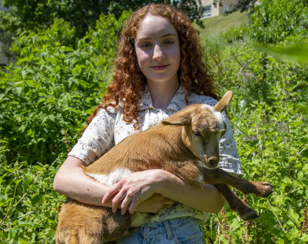 Floreal Crubaugh '20 holds a goat in the SLUG garden.